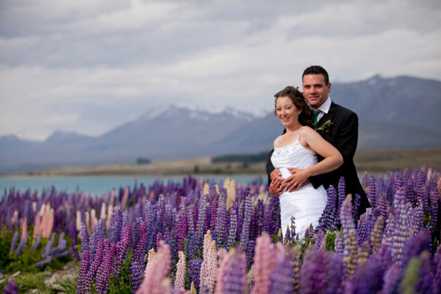 Bride and groom within lupin flowers